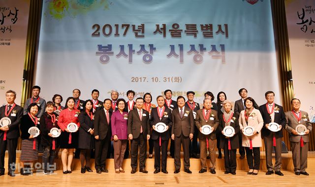 서울시와 한국일보가 공동주최한 '2017 서울특별시봉사상' 수상자들과 류경기(왼쪽에서 8번째) 행정1부시장, 이준희(오른쪽에서 6번째) 한국일보 사장이 31일 서울시청 8층 다목적홀에서 기념촬영을 하고 있다. 대상은 '어르신의 안부를 묻는 우유배달(왼쪽에서 9번째)'이 받았다. 신상순 선임기자