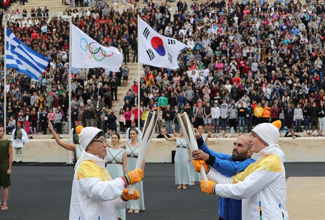 31일 그리스 아테네 파나티나이코 스타디움에서 열린 2018 평창동계올림픽 성화 인수식에서 김기훈(왼쪽)이 그리스 알파인 스키선수 이와니스 프리오이스에게 성화를 인계하고 있다. 아테네=연합뉴스