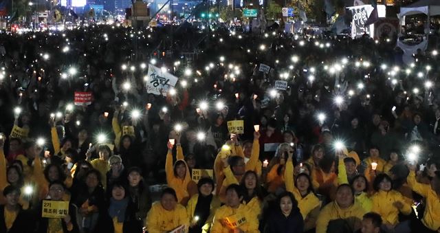 박근혜정권퇴진 비상국민행동 기록기념위원회 주최로 28일 서울 광화문광장에서 열린 촛불 1주년 기념대회 '촛불은 계속된다'에서 참석자들이 촛불을 밝히고 있다. 연합뉴스