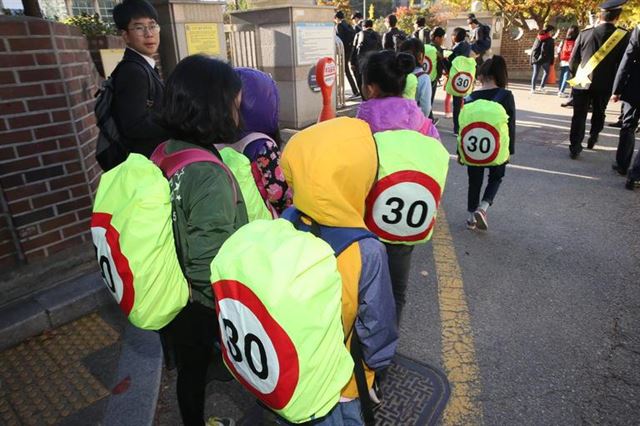 지난달 30일 오전 경남 창원시내의 한 학교 앞에서 학생들이 속도제한 안전덮개를 가방에 씌운 채 등교하고 있다. 연합뉴스