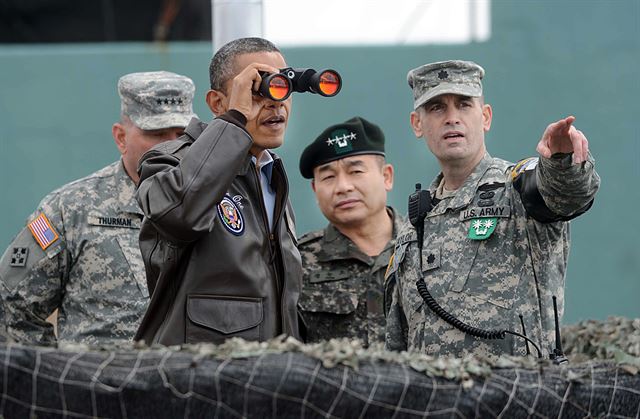 2012 서울 핵안보정상회의를 위해 25일 새벽 방한한 오바마 미 대통령이 비무장지대(DMZ) 내 오울렛 초소를 찾아 방탄 유리 뒤에서 쌍안경으로 북한 지역을 살펴보고 있다. 판문점 공동경비구역=사진공동취재단