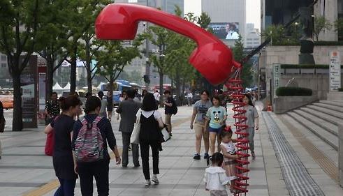 서울 종로구 세종문화회관 주변에 경찰이 아동학대 근절 캠페인의 하나로 설치한 ‘착한 신고 전화기’ 앞을 시민들이 지나가고 있다. ‘착한신고 전화기’는 사람이 가까이 다가오면 어린이 울음소리가 나오며 '시민들의 관심과 신고가 중요하다'는 메시지가 바닥에 표시된다. 연합뉴스