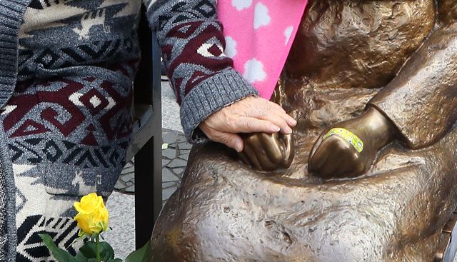 22일 오후 서울 종로구 옛 주한일본대사관 앞에서 정대협 주최 '일본군 위안부 문제 해결을 위한 정기 수요시위'에서 참석한 시민이 소녀상의 손을 잡아주고 있다. 연합뉴스