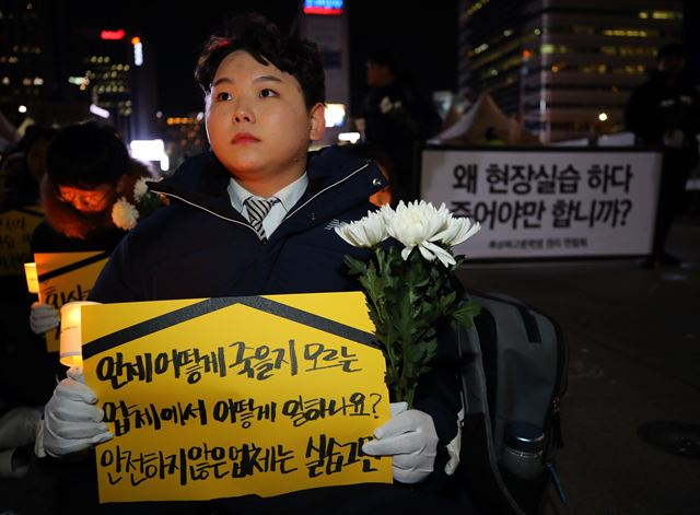 22일 오후 서울 광화문광장 이순신 동상 앞에서 열린 '특성화고 실습생 고 이민호 군 추모문화제'에서 참가자가 피켓을 들고 앉아있다. 연합뉴스