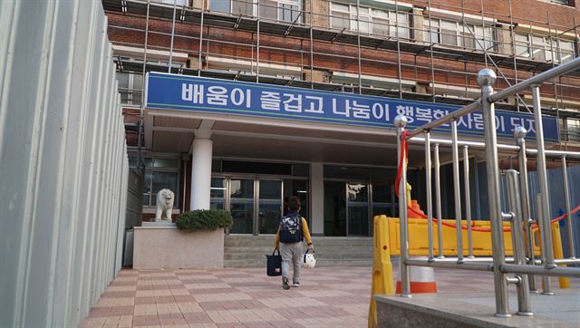 경북 포항 장성초가 29일 지진으로 피해를 입은 포항지역 학교 중 가장 마지막으로 수업을 재개한 가운데 건물을 에워 싼 펜스 사이로 한 어린이가 안전모를 들고 등교하고 있다. 김정혜기자 kjh@hankookilbo.com