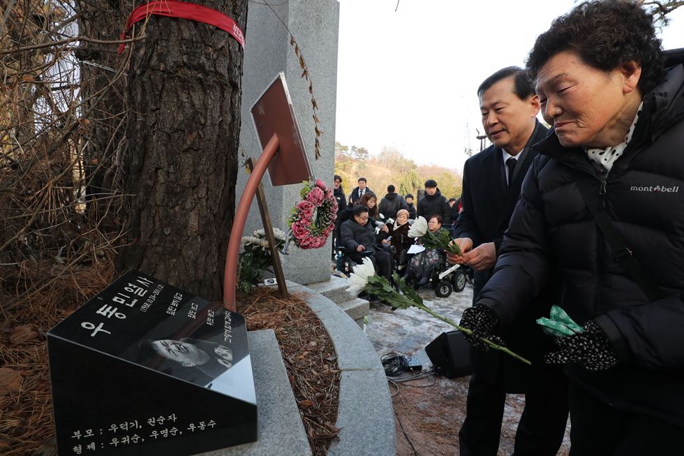 2일 경기도 남양주 모란공원에서 열린 고(故) 우동민 열사 7주기 추모행사에서 유족 권순자 씨가 이성호 국가인권위원장과 묘소에 헌화 후 묘비를 쓰다듬고 있다. 국가인권위원회는 2010년 장애인단체의 인권위 점거농성에 참여하다 숨진 우 씨에 대한 인권침해 사실을 인정하고 공식 사과했다. 점거농성 당시 인권위는 전기 공급과 난방·엘리베이터 등을 가동을 하지 않아 장애인활동가들에 대해 인권침해 행위를 했다. . 남양주=연합뉴스