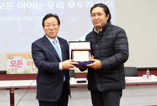 2013년부터 강원도내 시골 학교를 찾아 알록달록 색을 입히는 재능기부를 하고 있는 김재식(오른쪽) 씨가 지난해 11월 강릉 녹색도시체험센터에서 민병희 강원교육감으로부터 감사패를 받고 있다. 강원교육청 제공