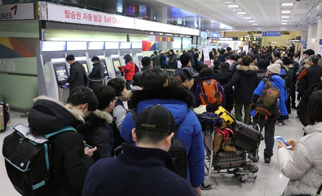 12일 오전 제주공항의 항공기 운항이 재개되기도 전에 전날 결항 항공편 승객들이 항공사 발권 카운터 앞에 줄을 서서 기다리고 있다. 연합뉴스.