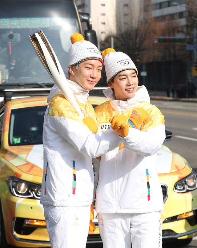 아이돌 그룹 위너의 이승훈과 김진우가 지난 5일 오후 경기도 수원시 수원종합버스터미널 앞에서 2018 평창동계올림픽 성화 봉송을 하고 있다.연합뉴스