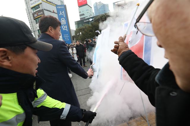 경찰이 불붙은 인공기와 한반도기에 소화기를 분사해 불을 끄고 있다. 연합뉴스