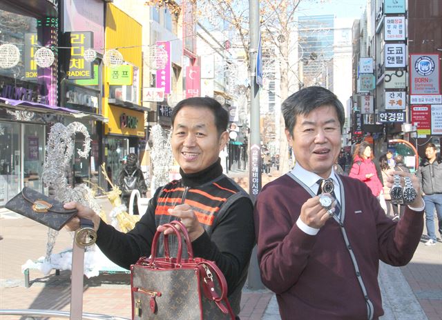 조용달(왼쪽) 동문사 대표와 이준희 명품시계 대표가 교동시장 입구에서 자신들이 수리한 제품을 들고 환하게 웃고 있다. 김민규기자 whitekmg@hankookilbo.com