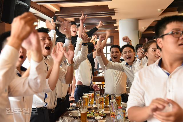 23일 저녁 베트남 축구팀이 카타르와의 준결승전에서 동점골을 넣자 호찌민 시내 음식점에 모여 응원하던 시민들이 일제히 자리에서 일어나 열광하고 있다.