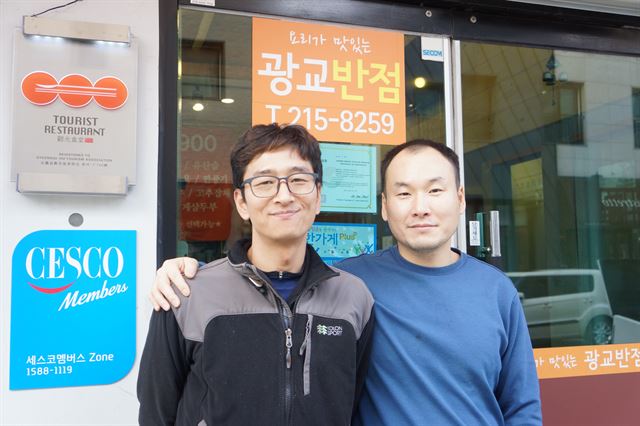 아르바이트생들에게도 생활임금을 기준으로 임금을 지급, 경기 수원시의 ‘착한 가게 플러스’ 인증을 받은 배영준(오른쪽) 광교반점 대표가 영통구에 있는 가게 앞에서 한 직원과 어깨동무를 하고 웃고 있다. 수원시 제공