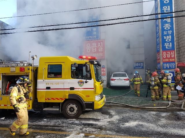 소방관들이 26일 오전 경남 밀양시 가곡동 세종병원에서 화재 진압을 하는 동안 병원 내부에서 연기가 뿜어져 나오고 있다. 밀양=연합뉴스