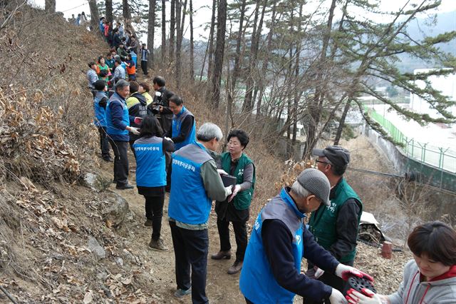 지난달 강원 횡성군 공근면 창봉리 홀몸노인 집을 방문한 자원봉사자들이 인간 띠를 만들어 연탄을 전달하고 있다. 횡성군 자원봉사센터 제공