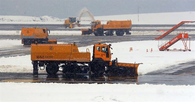 8일 제주공항에 또다시 폭설이 내려 항공기 운항이 전면 중단됐다. 이날 오전 한국공항공사 제설차량들이 활주로의 눈을 치우고 있다. 연합뉴스.