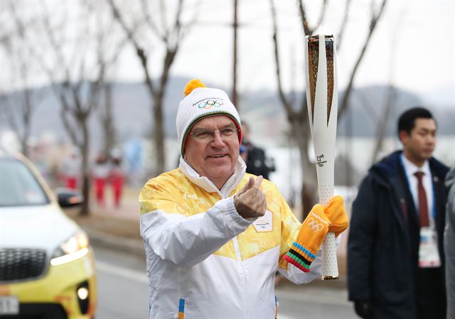 토마스 바흐 국제올림픽위원회(IOC) 위원장이 평창동계올림픽 개막일인 9일 오전 알펜시아 올림픽파크 인근에서 성화봉송을 하며 손가락으로 하트를 만들어보이고 있다.. 평창=연합뉴스