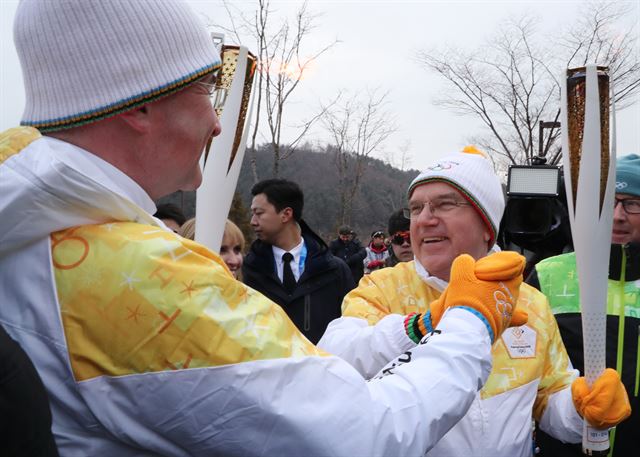 토마스 바흐 국제올림픽위원회(IOC) 위원장(오른쪽)이 평창동계올림픽 개막일인 9일 오전 알펜시아 올림픽파크 인근에서 성화봉송을 한 뒤 미로슬라프 라이착 유엔총회 의장에게 전달하고 있다. 평창=연합뉴스