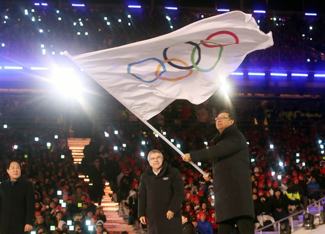 25일 강원도 평창 올림픽스타디움에서 열린 평창동계올림픽 폐회식에서 차기 개최 도시인 중국 베이징시 천지닝 시장이 올림픽기를 건네 받고 휘날리고 있다. 평창=연합뉴스