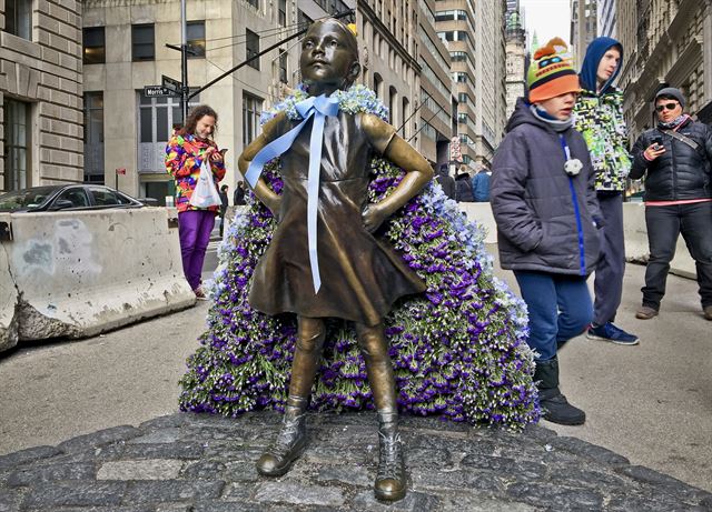 세계 여성의 날을 맞은 8일(현지시간) 뉴욕의 증권거래소 앞에 세워진 '겁없는 소녀(Fearless Girl)'상에 화려한 꽃다발로 만든 망토가 걸쳐져 있다. AP 연합뉴스