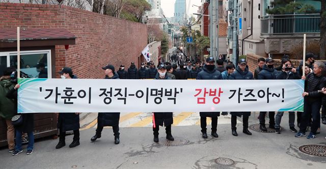 14일 오전 서울 강남구 논현동 이명박 전 대통령의 자택 앞에서 시위에 나선 시민들이 이명박 전 대통령의 구속을 촉구하는 현수막을 들고 있다. 연합뉴스