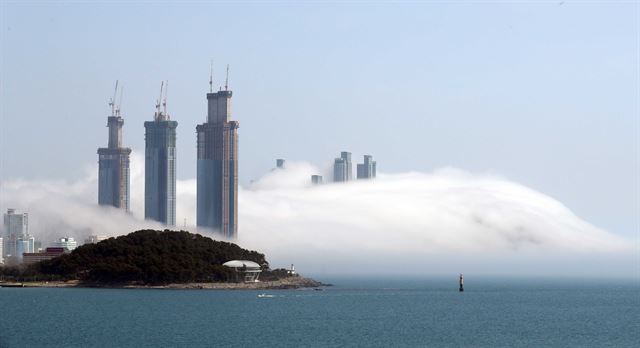 14일 부산 해운대 앞바다에 발생한 해무가 동백섬과 해운대해수욕장, 달맞이 언덕 일대를 뒤덮어 장관을 이루고 있다. 동백섬 뒤편으로 최고 101층 규모로 공사 중인 엘시티 건물이 보인다. 부산=연합뉴스