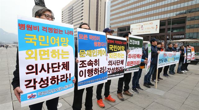 국민건강보험노동조합과 전국보건의료산업노조 등 양대 노조 관계자들이 18일 오후 서울 광화문광장에서 의료계의 문재인 케어 반대 집회를 "극단적 집단이기주의"라고 비판하는 피켓 시위를 하고 있다. 뉴스 1