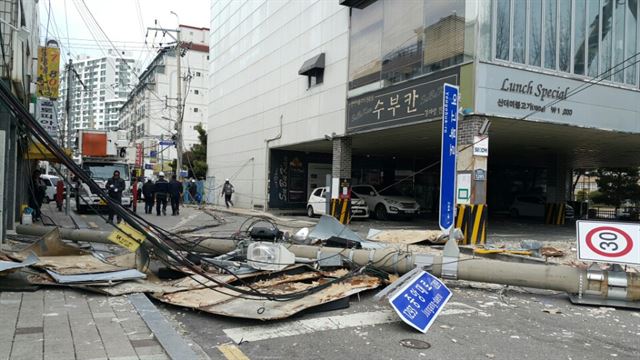 부산지역에 강풍특보가 발효된 20일 오전 9시 50분께 부산 동래구에 있는 한 음식점 건물에서 상층부 마감재가 강풍으로 탈락하면서 전신주와 함께 지상으로 떨어져 아수라장으로 변해 있다. 부산시소방안전본부 제공=연합뉴스