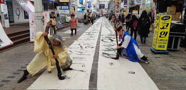 26일 울산시 중구 젊음의 거리에서 김지영 한국서예 퍼포먼스협회 회장과 김동욱 독도사랑 예술인연합회 회장이 2인 1조가 되어 안중근 의사 순국 108주년 추모 서예 퍼포먼스를 하고 있다.김동욱 회장 제공=연합뉴스