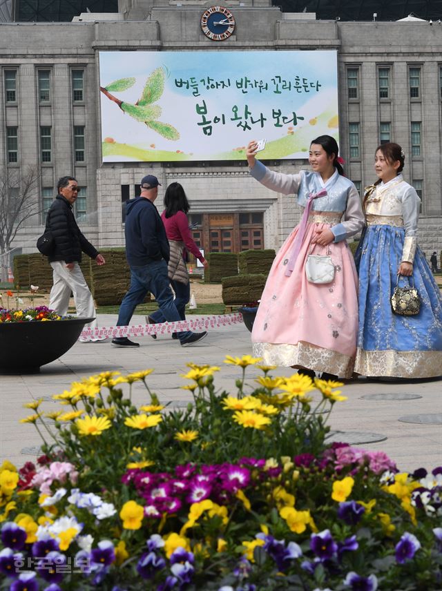 27일 서울 중구 서울도서관 외벽에 설치된 꿈새김판이 글귀가 바뀐 가운데 외국인 관광객이 한복을 입고 사진을 찍고 있다. 홍인기 기자