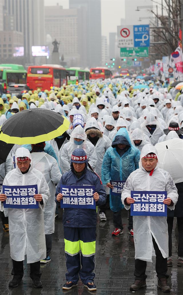 한국지엠노조원들이 지난달 28일 오후 서울 세종로소공원 앞에서 열린 GM문제해결을 위한 금속노조결의대회에서 군산공장 폐쇄철회와 구조조정 중단을 요구하며 손팻말을 들고 묵념하고 있다. 연합뉴스