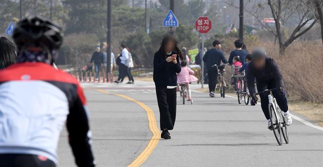 지난 25일 한강시민공원 여의도 지구 자전거도로에서 한 자전거 이용자가 스마트폰을 이용하며 이동하고 있는 보행자를 피해 지나가고 있다. 한강 공원 등 휴일 많은 시민이 몰리는 곳에서는 자전거 이동을 고려하지 않고 이동하는 보행자가 많아 각별한 주의가 필요하다