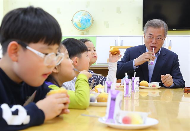 문재인 대통령이 4일 오후 서울 성동구 경동초등학교를 방문, 온종일 돌봄 정책 간담회를 하기 앞서 독서활동을 하고 있는 돌봄 교실을 방문해 어린이들에게 간식을 나눠준 뒤 함께 맛보고 있다. 연합뉴스