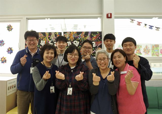 대구 북구 행복누리 기억학교 직원들이 손가락 하트를 날리고 있다. 뒷줄 왼쪽부터 시계방향으로 김기덕 소장과 전찬후, 류민혁, 김두진 사회복지사, 강동우 복무요원, 이순란 조리사, 이정희 간호사, 이예진 팀장, 홍영숙 사회복지사. 윤희정기자 yooni@hankookilbo.com