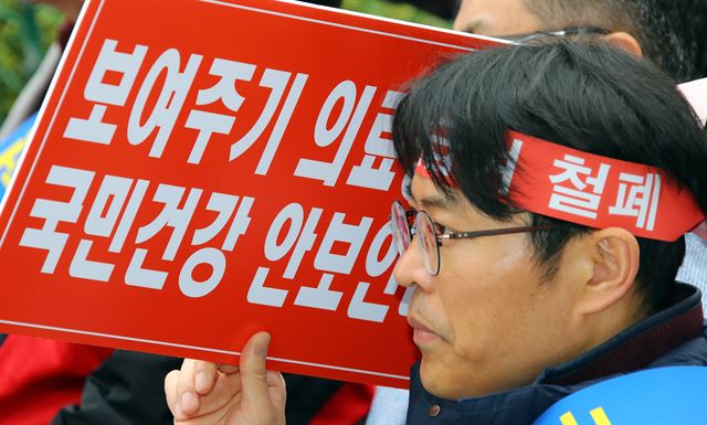 대한의사협회 국민건강수호 비상대책위원회가 지난달 18일 서울 광화문 동화면세점 앞에서 연 '문재인 케어 저지를 위한 제1차 전국의사 대표자 회의'에서 한 참가자가 피켓 시위를 하고 있다. 연합뉴스