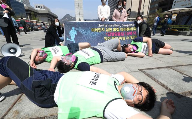 환경보건시민센터 회원들이 10일 서울 광화문 광장에서 ‘서울국제마라톤’ 등 국내 주요 마라톤 대회명을 가슴에 달고 방독면을 쓴 채 달리다 숨차하며 쓰러지는 퍼포먼스를 하고 있다. 연합뉴스