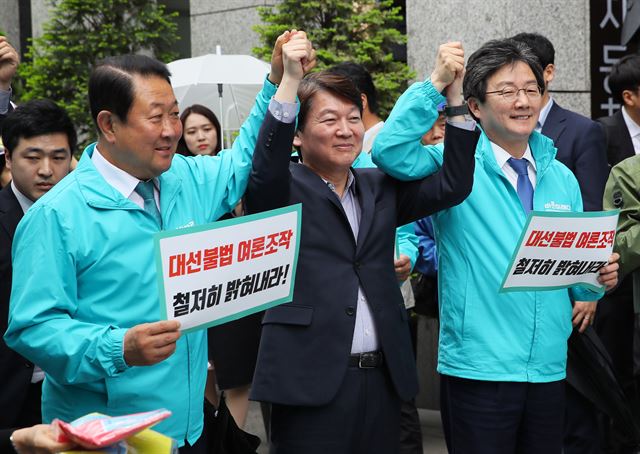 바른미래당 박주선(왼쪽부터) 공동대표와 안철수 서울시장 후보, 유승민 공동대표가 22일 서울 광화문 광장 인근에서 열린 민주당원 댓글조작 규탄 대회에서 손을 들어 올리고 있다. 연합뉴스