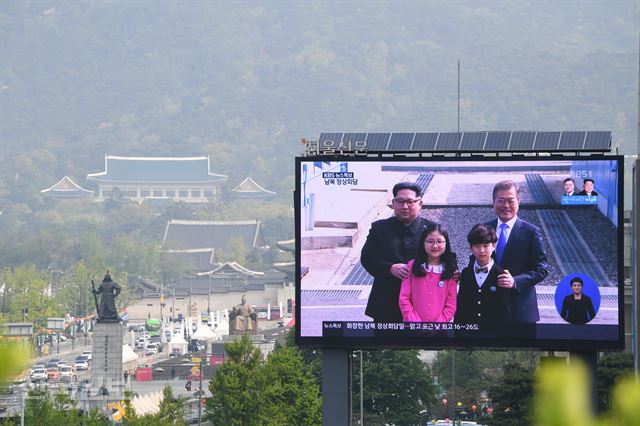 27일 오전 문재인 대통령과 김정은 위원장이 판문점에서 어린이들과 기념사진을 찍는 모습이 서울 광화문 청와대를 배경으로 한 전광판에 중계되고 있다. 신상순 선임기자