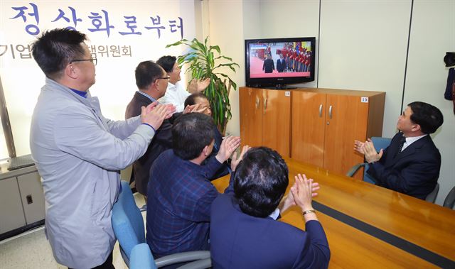 개성공단기업협회 신한용 회장을 비롯한 입주기업 관계자들이 27일 오전 서울 여의도 사무실에서 개성공단 재가동의 불씨가 살아나길 기대하며 역사적인 남북정상의 만남을 TV를 통해 지켜보다 박수치고 있다. 연합뉴스