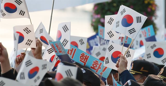 재향군인회 회원들이 27일 오전 서울 광화문 정부서울청사 앞에서 남북정상회담을 위해 판문점으로 향하는 문재인 대통령 일행을 향해 태극기와 '비핵화'란 문구가 새겨진 손팻말을 흔들고 있다. 연합뉴스