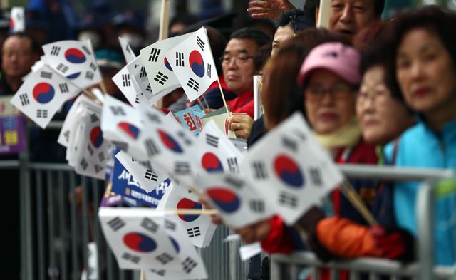 27일 오전 서울 광화문 정부서울청사 앞에서 재향군인회 회원들이 판문점으로 향하는 문재인 대통령 일행을 태운 차량이 지나가기를 기다리며 태극기를 들고 기다리고 있다. 연합뉴스