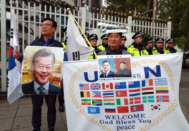 27일 오전 서울 광화문 정부서울청사 앞에서 재향군인회 회원들이 판문점으로 향하는 문재인 대통령 일행을 태운 차량이 지나가기를 기다리며 현수막을 펼친 채 기다리고 있다. 연합뉴스