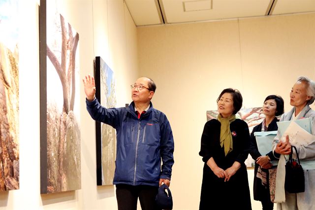 김휘동 전 안동시장이 안동 예술의 전당에서 '솔 바위를 찿아서'라는 제목으로 사진 전시회를 개최하고 관람객들에게 설명하고 있다.