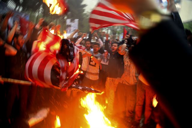 도널드 트럼프 미 대통령이 국제사회의 우려에도 불구하고 이란핵합의(JCPOA·포괄적 공동행동계획) 탈퇴 선언을 한 가운데 9일(현지시간) 이란 테헤란의 옛 미국 대사관 앞에서 시민들이 성조기, 트럼프 사진 등을 불태우며 격렬한 반미시위를 하고 있다. AP 연합뉴스