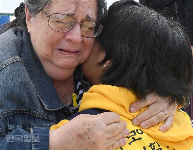 10일 전남 목포신항에서 세월호가 세워지는 장면을 함께 본 외국인 추모객이 가족들을 위로하고 있다. 서재훈기자