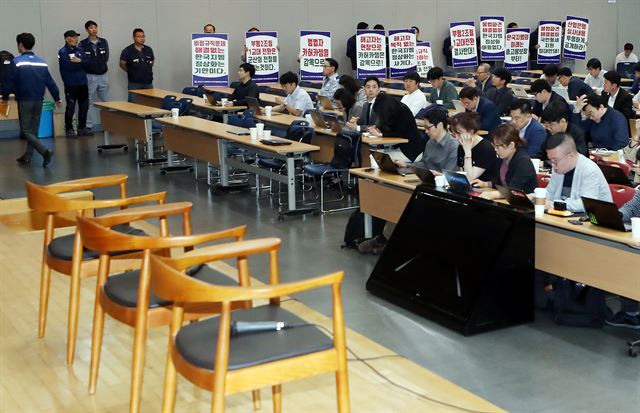 14일 오전 인천 부평구 한국지엠 부평공장 홍보관 대강당에서 금속노조 인천지부 한국지엠비정규직지회 노조원들이 손 팻말을 들고 서 있다. 노조원들 사위로 이날 이곳에서 열릴 예정이었던 한국지엠 경영 정상화 기자회견은 취소됐다. 연합뉴스