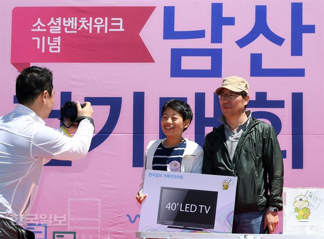 제474회 한국일보 거북이마라톤 '소셜벤처 위크 기념 남산 걷기대회'가 19일 서울 남산 백범광장에서 열린 가운데 식후행사의 행운권 추첨에서 40인치 LED TV를 받은 한 학생이 이날 명예회장을 맡은 김종각 한국사회적기업진흥원 기획관리본부장대회와 기념촬영을 하고 있다. 홍인기 기자