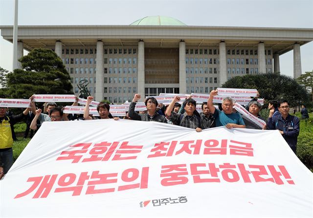 21일 오후 서울 여의도 국회 앞에서 최저임금산입범위 확대 저지 총력투쟁에 나선 민주노총 조합원들이 국회 앞마당으로 들어와 시위를 벌이며 구호를 외치고 있다. 연합뉴스