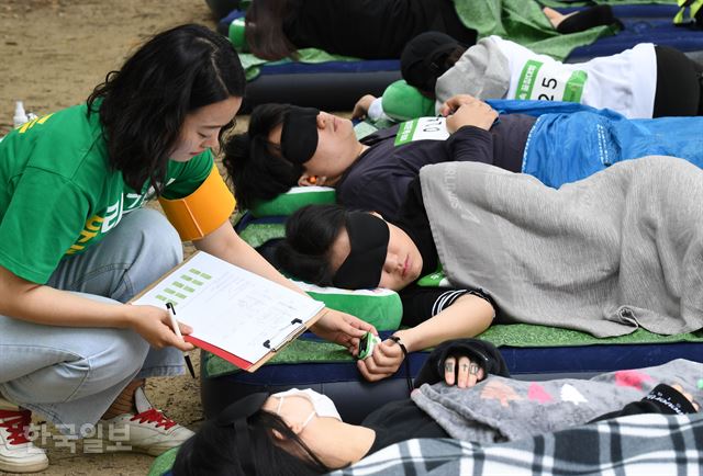 27일 서울 성동구 서울숲에서 '2018 우푸푸 숲속 꿀잠 대회'가 열린 가운데 관계자들이 수면 중인 참가자의 심박수를 체크하고 있다. 홍인기 기자