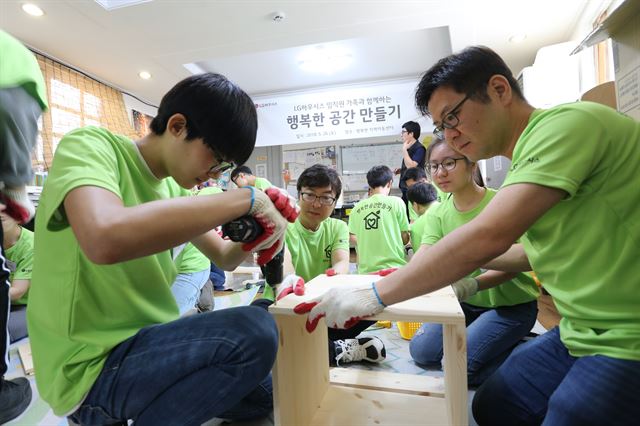 LG하우시스 직원과 자녀들이 26일 서울 동대문구 이문동의 행복한 지역아동센터에서 아이들이 사용할 사물함 등 DIY 가구를 조립하고 있다. LG하우시스 제공